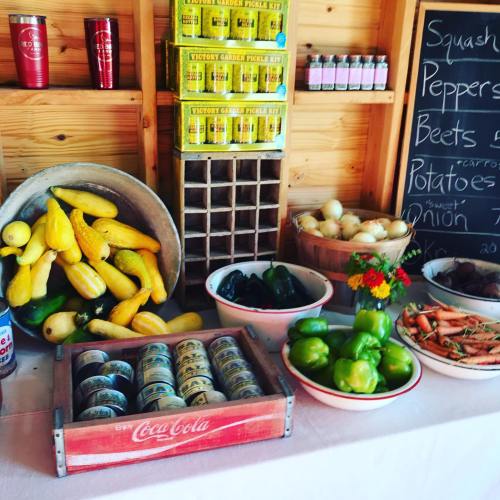 A rustic display of fresh vegetables, including squash, peppers, beets, and potatoes, in a wooden market setting.