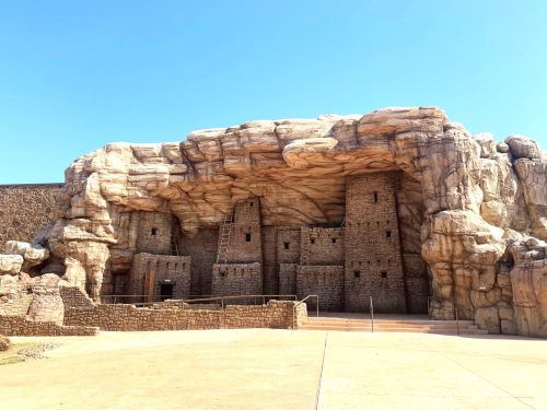 A rock formation resembling ancient ruins, with stone structures and a clear blue sky above.
