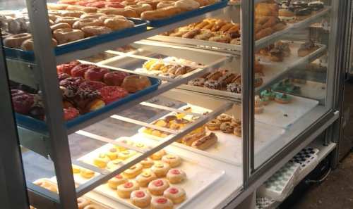 A display case filled with a variety of colorful donuts and pastries, showcasing different shapes and toppings.