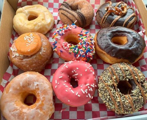 A box of assorted donuts, featuring various flavors and toppings, including sprinkles, chocolate, and glazed options.