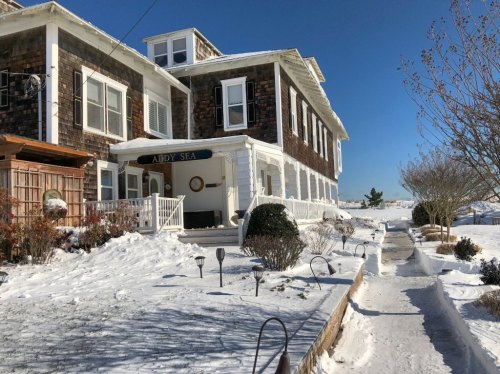 A snow-covered building with a sign reading "Addy Sea," surrounded by a clear blue sky and winter scenery.