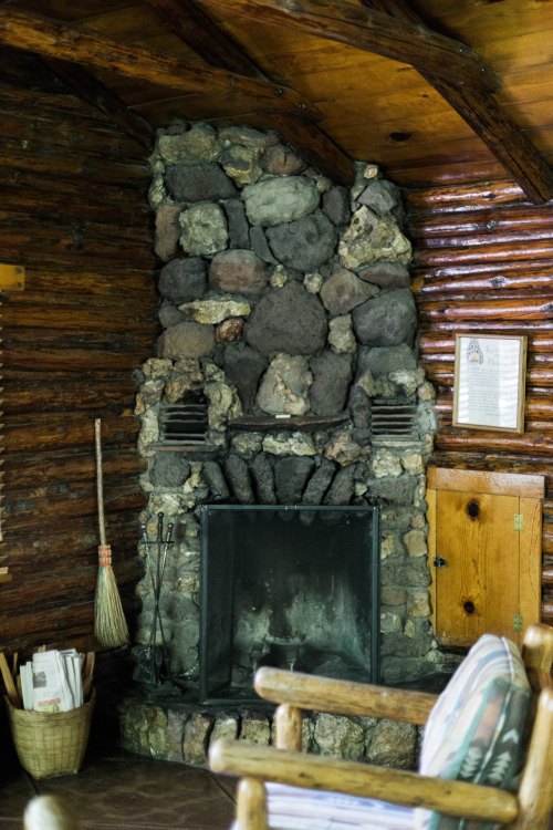 Cozy cabin interior featuring a stone fireplace, wooden walls, and rustic furniture.