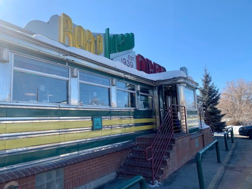 A colorful diner with a retro sign, established in 1939, featuring green and yellow stripes and a snowy entrance.
