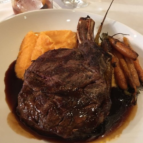 A plate featuring a juicy ribeye steak, creamy mashed sweet potatoes, and roasted carrots in a rich sauce.