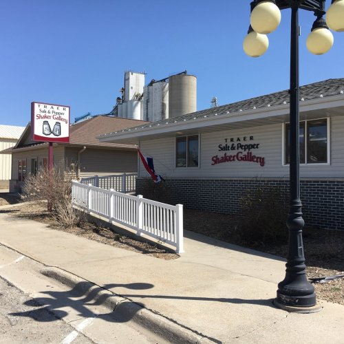 Exterior view of the Traer Salt & Pepper Shaker Gallery, featuring a sign and nearby industrial buildings.