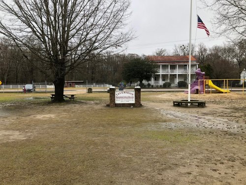 A park with a sign reading "Lavernock," featuring a playground, a tree, and a building in the background on a cloudy day.