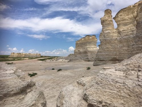 A vast landscape featuring towering white rock formations under a blue sky with scattered clouds.