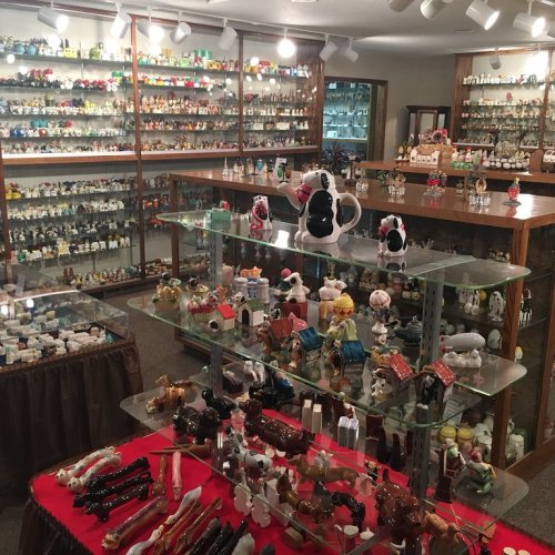 A display room filled with various collectible figurines and ceramics on glass shelves and tables.