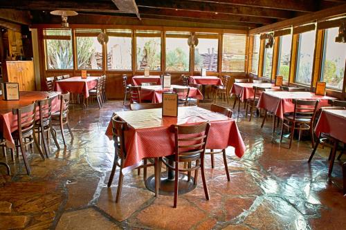 Cozy restaurant interior with wooden beams, stone floor, and tables set with red checkered tablecloths.
