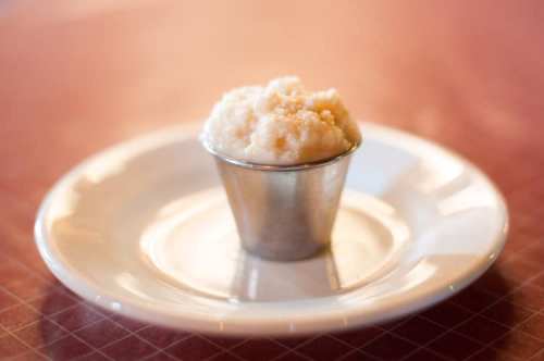 A small metal cup filled with creamy, light-colored dessert on a white plate.