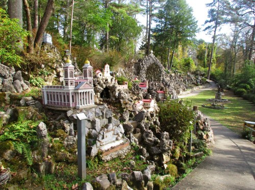 A scenic garden featuring miniature buildings and rocky landscapes, surrounded by trees and pathways.
