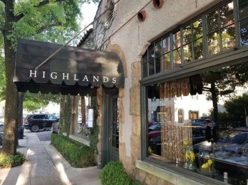 Exterior of a restaurant named "Highlands," featuring a black awning and large windows with a view of the street.