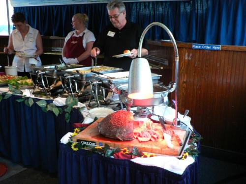A buffet setup with a carved roast, salad, and staff serving food in a decorated dining area.