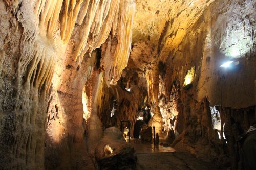 A dimly lit cave with dramatic rock formations and stalactites, showcasing natural textures and colors.