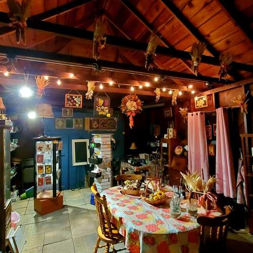 Cozy interior of a rustic room with wooden beams, warm lighting, and decorated with art, plants, and a dining table.