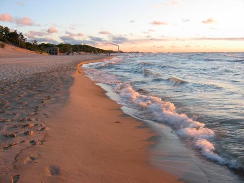 A serene beach at sunset, with gentle waves lapping at the shore and footprints in the sand.