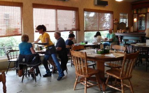 A cozy restaurant scene with diners at tables and a server attending to customers by the window.