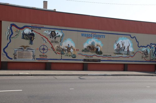 Mural depicting the history of Wasco County, featuring maps, illustrations of pioneers, and key locations.