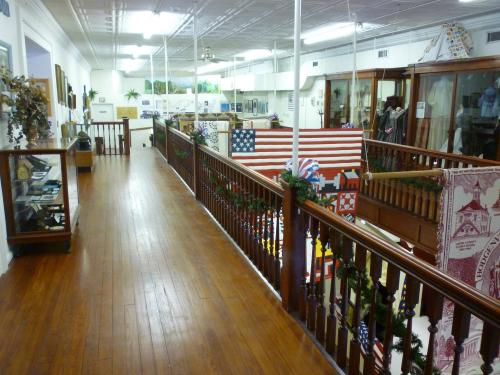 A wooden balcony overlooking a museum exhibit with displays and decorations, featuring quilts and historical artifacts.