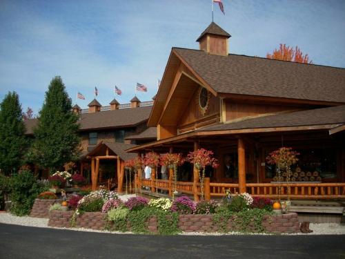 A rustic wooden lodge with a stone flower bed, colorful flowers, and American flags on the roof against a clear sky.