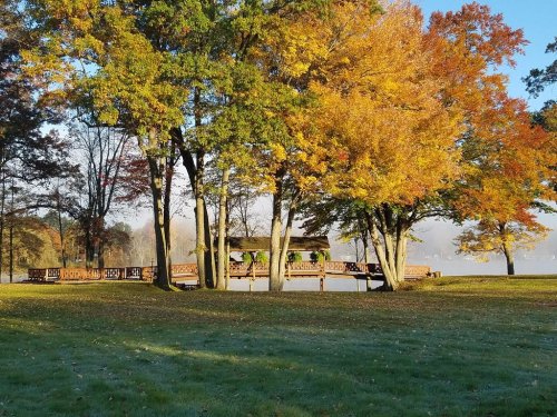 A wooden dock surrounded by vibrant autumn trees and a misty lake in the background.