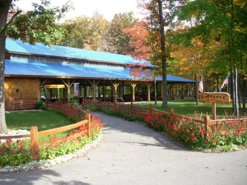 A scenic entrance to a wooden building surrounded by colorful autumn trees and vibrant flower beds.