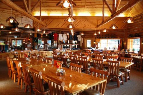 A spacious wooden dining area with long tables, rustic decor, and warm lighting, creating a cozy atmosphere.