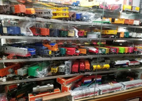 A display case filled with various model trains and toy train cars in different colors and styles.