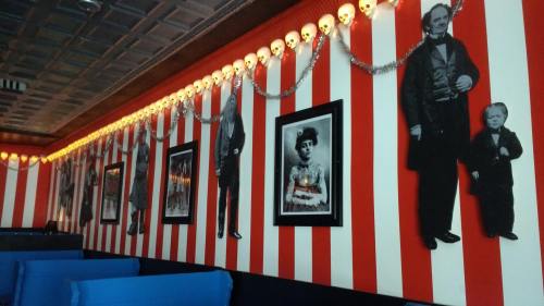 A striped wall adorned with vintage black-and-white portraits and decorative skull lights.