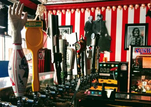 A row of colorful beer taps in a quirky bar with vintage decor and a playful atmosphere.