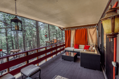 Cozy porch with seating, colorful curtains, and a view of trees, creating a serene outdoor space.