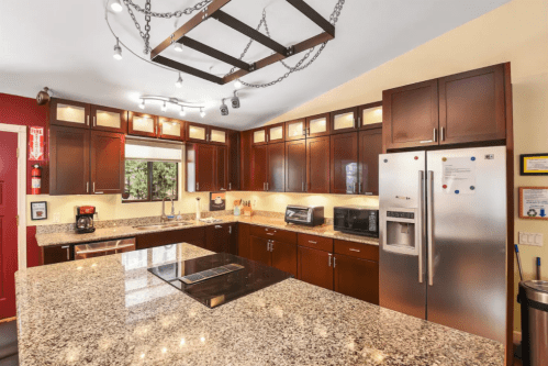 Modern kitchen with dark wood cabinets, granite countertops, stainless steel appliances, and a central island.
