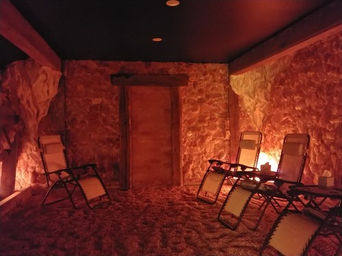 A cozy, dimly lit room with stone walls, featuring reclining chairs and a warm ambiance.