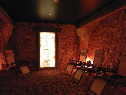A tranquil salt room with reclining chairs, soft lighting, and a glowing salt wall, creating a relaxing atmosphere.