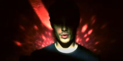 A silhouette of a person against a red and orange abstract background, creating a dramatic and moody atmosphere.