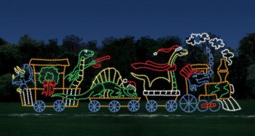 A colorful light display of a train with dinosaur figures, set against a dark evening sky.