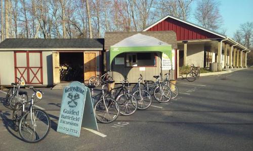 Bicycles lined up outside a building with a sign for guided battlefield excursions. Trees in the background.