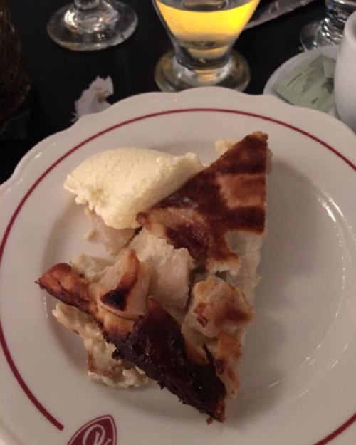 A slice of pie with a flaky crust, served with a scoop of vanilla ice cream on a white plate.
