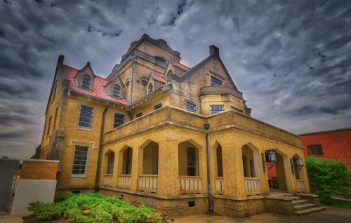 Historic building with a unique architectural style, featuring a textured facade and a dramatic sky overhead.