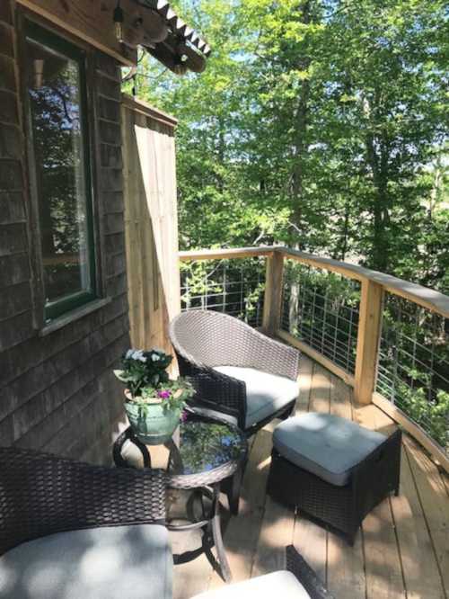 Cozy outdoor seating area on a wooden deck surrounded by lush greenery.