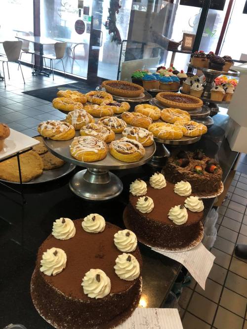 A display of various baked goods, including cakes, pastries, and cookies, in a bakery setting.