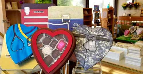Four heart-shaped boxes of chocolates, each with unique designs: a doctor's coat, a toolbox, a fishing theme, and camouflage.