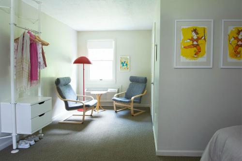 Cozy room with two chairs, a lamp, a small table, and wall art, featuring light colors and a minimalist design.