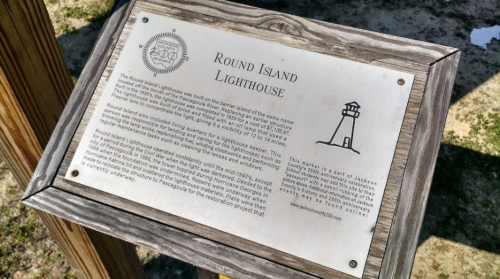 Plaque detailing the history of Round Island Lighthouse, featuring a lighthouse illustration and historical information.