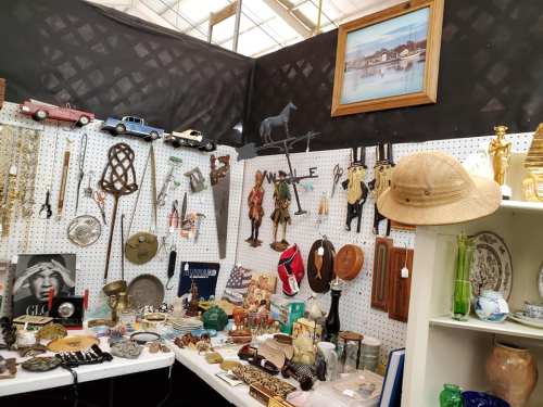 A display of various antiques and collectibles, including jewelry, figurines, and vintage items on a pegboard.