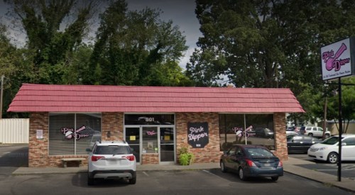 Exterior of a brick building with a pink roof, featuring the "Pink Dipper" sign and parked cars in front.