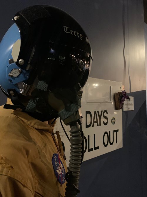 A mannequin in a flight suit and helmet stands next to a sign that reads "DAYS ROLL OUT."