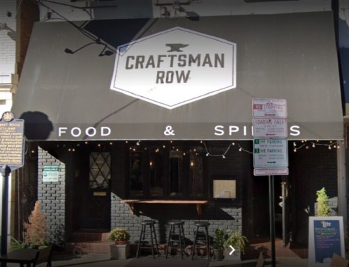 Exterior of Craftsman Row, a restaurant with a black awning, outdoor seating, and string lights.
