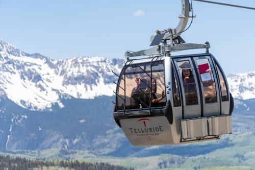 A gondola ascends over snow-capped mountains, with passengers enjoying the scenic view in Telluride, Colorado.