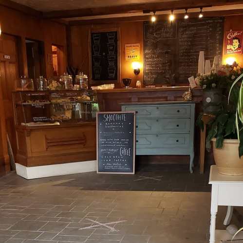 Cozy farm store interior with wooden decor, a chalkboard menu, and a display of snacks and coffee options.